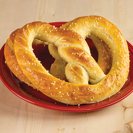 2 pretzels with salt on a red plate with wooden table as backdrop